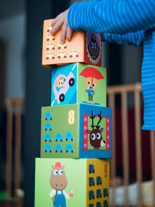 A child playing indoors, stacking colorful wooden toy blocks with joyful illustrations.